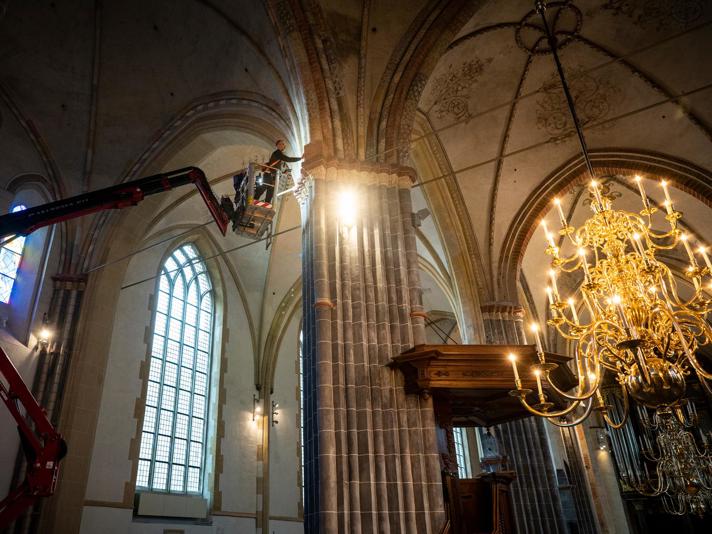 Een bouwkundig op een hoogwerker onderzoekt de gewelven van de Groningse Martinikerk