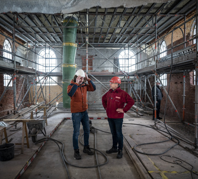 Bouwkundige van Stichting Oude Groninger Kerken en restauratie architect staan in de kerk die wordt versterkt.