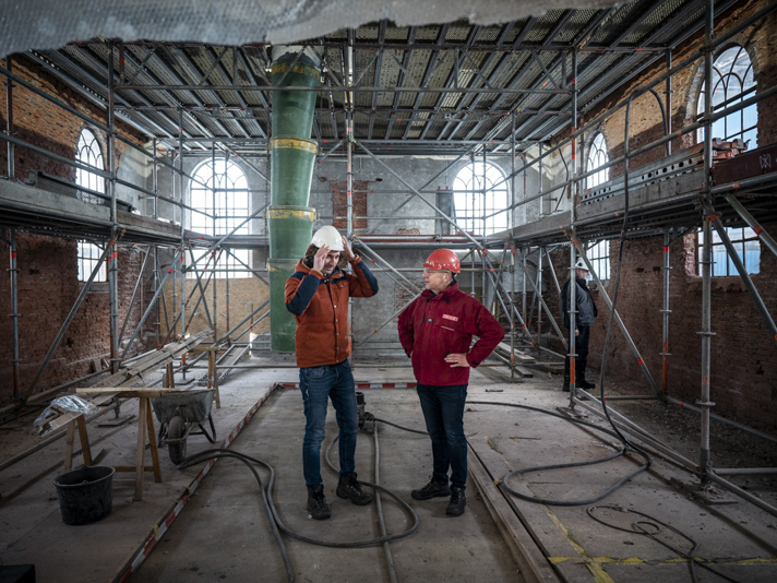 Bouwkundige van Stichting Oude Groninger Kerken en restauratie architect staan in de kerk die wordt versterkt.