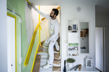 Persoon stukt een wand naast de trap naar de bovenverdieping in een huis.