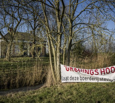 Een lege boerderij met op de voorgrond een spandoek met de tekst 'Gronings hoop, laat deze boerderij stevig staan'' 