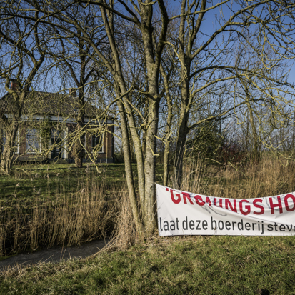 Een lege boerderij met op de voorgrond een spandoek met de tekst 'Gronings hoop, laat deze boerderij stevig staan'' 