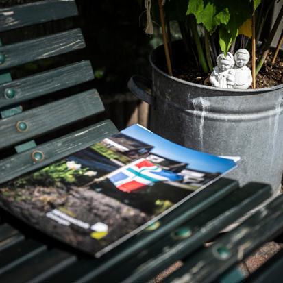 Een map van Instituut Mijnbouwschade Groningen ligt op een tuinbank met ernaast een plantenbak waarin een klein standbeeldje neerkijkt op de map.