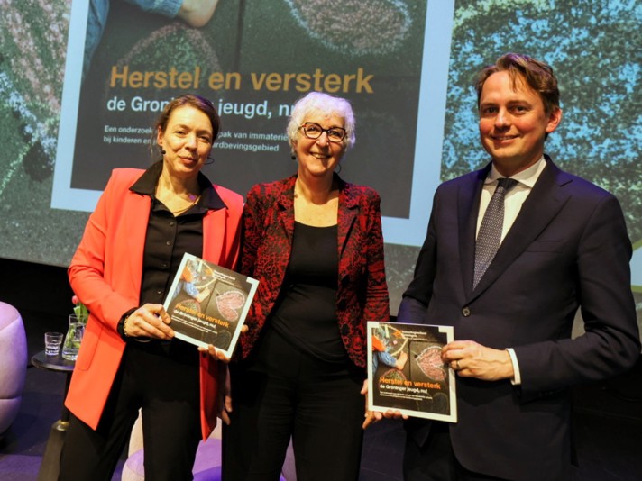 Susan Top (links) en Henk Nijboer (rechts) nemen onderzoeksrapport in ontvangst van IMG-bestuurslid Els van Schie. 