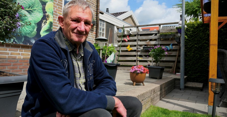 Remie Warries zittend op de stoep in zijn zomerse tuin