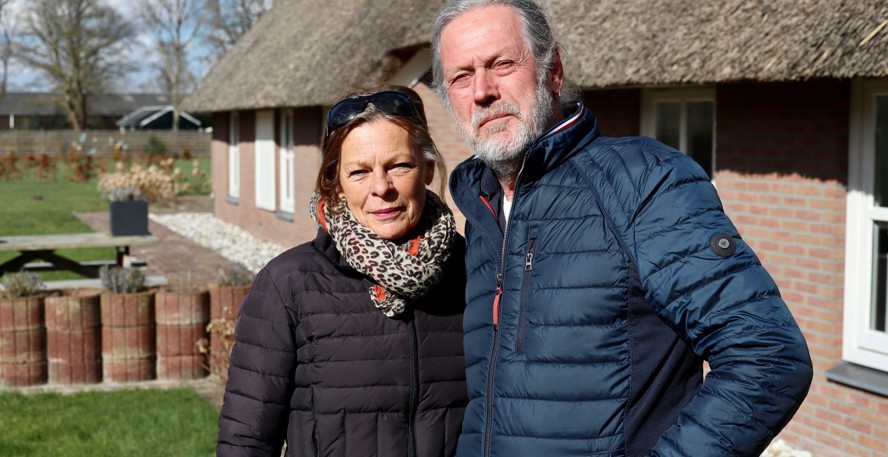 Fien Weeber en Ton Bakker staan met warme jassen aan in de zon voor hun rietgedekte boerderij 