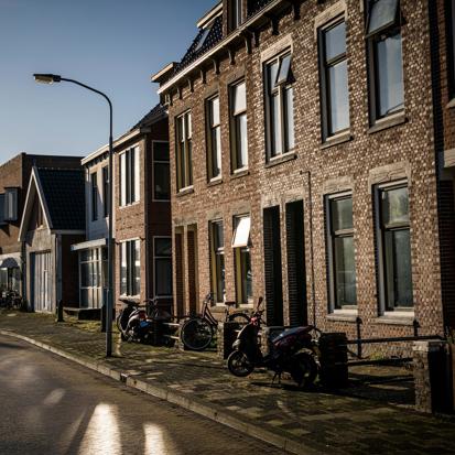 Een rij woningen in de zon met een blauwe lucht op de achtergrond.