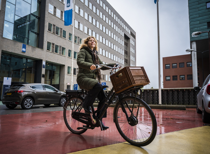 medewerker op de fiets voor het gebouw