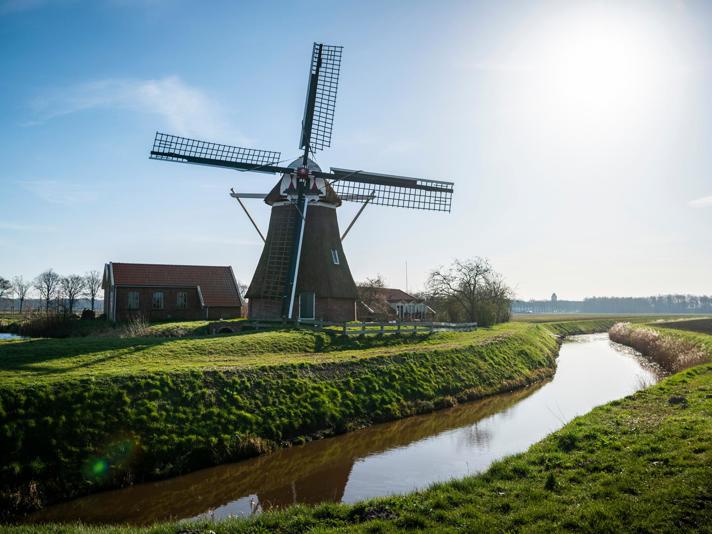 Een grote molen onder een zonnige, helderblauwe hemel.