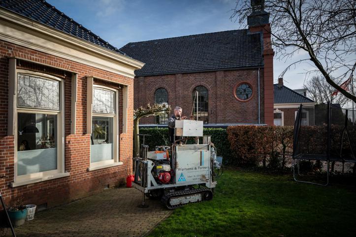 In de tuin van een woning wordt constructief onderzoek uitgevoerd.