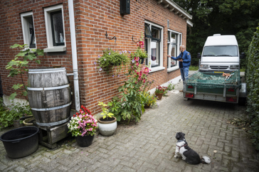 Een persoon bekijkt de buitenmuur van een woning en onderzoekt deze op schade.