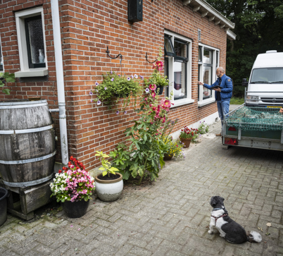 Een persoon bekijkt de buitenmuur van een woning en onderzoekt deze op schade.