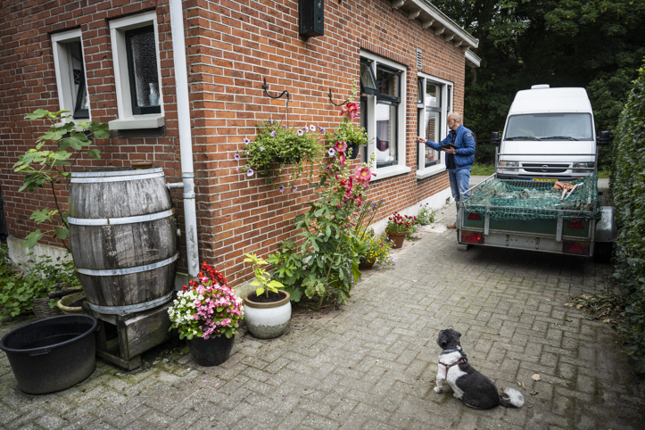 Een persoon bekijkt de buitenmuur van een woning en onderzoekt deze op schade.