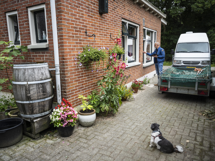 Een persoon bekijkt de buitenmuur van een woning en onderzoekt deze op schade.